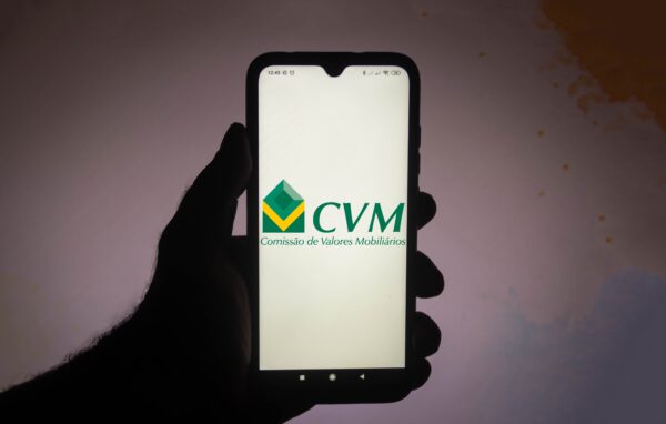 Mão segura celular com logotipo da CVM.