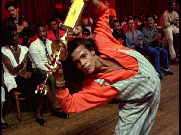 Dançarino de ballroom se dobra para frente enquanto segura um troféu