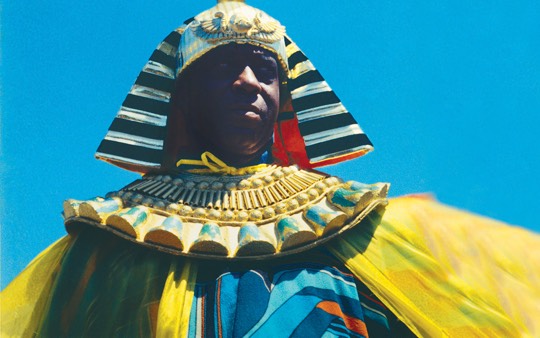 Homens negro com trajes egípcios está de pé contra o céu azul