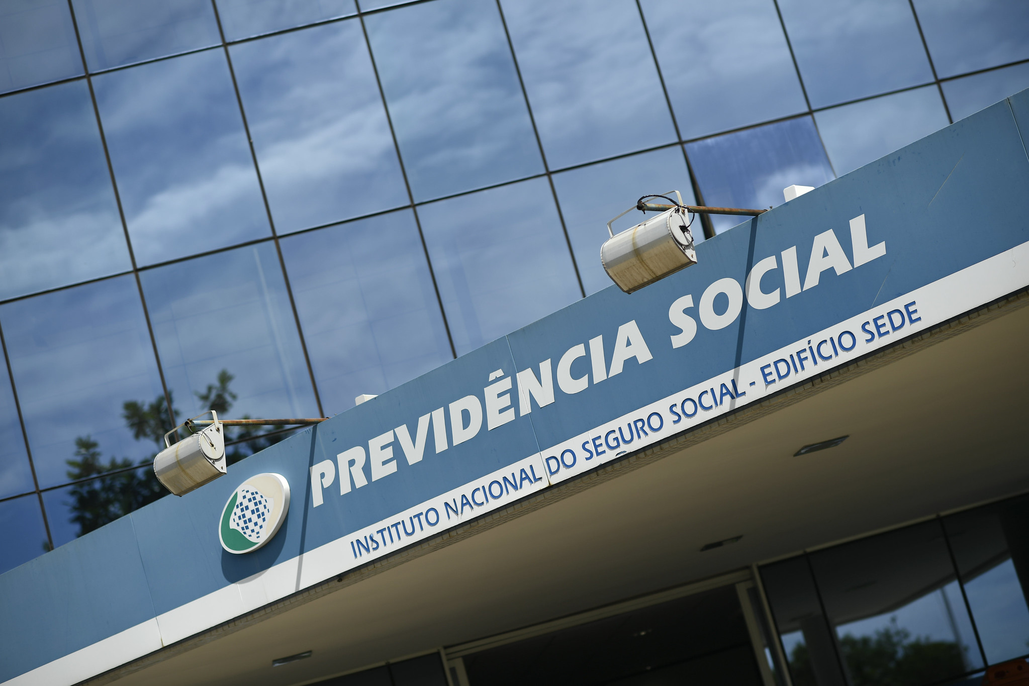 Fachada de prédio de vidro com placa que lê "Previdência Social - Instituto Nacional do Seguro Social, edifício sede"