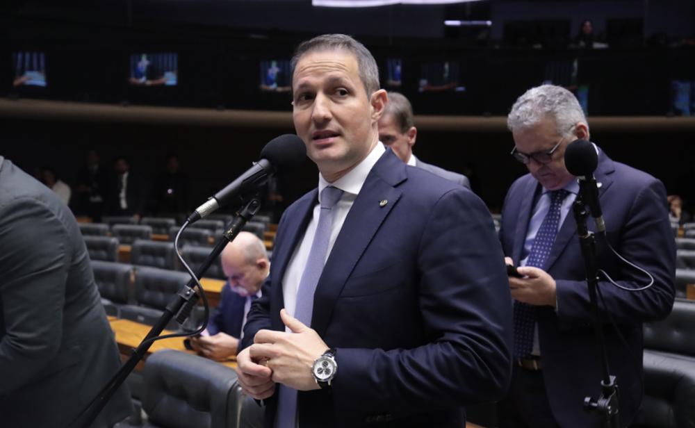 Guilherme Derrite na Câmara dos Deputados. Ele é um homem branco, usa terno e gravata e fala em um microfone