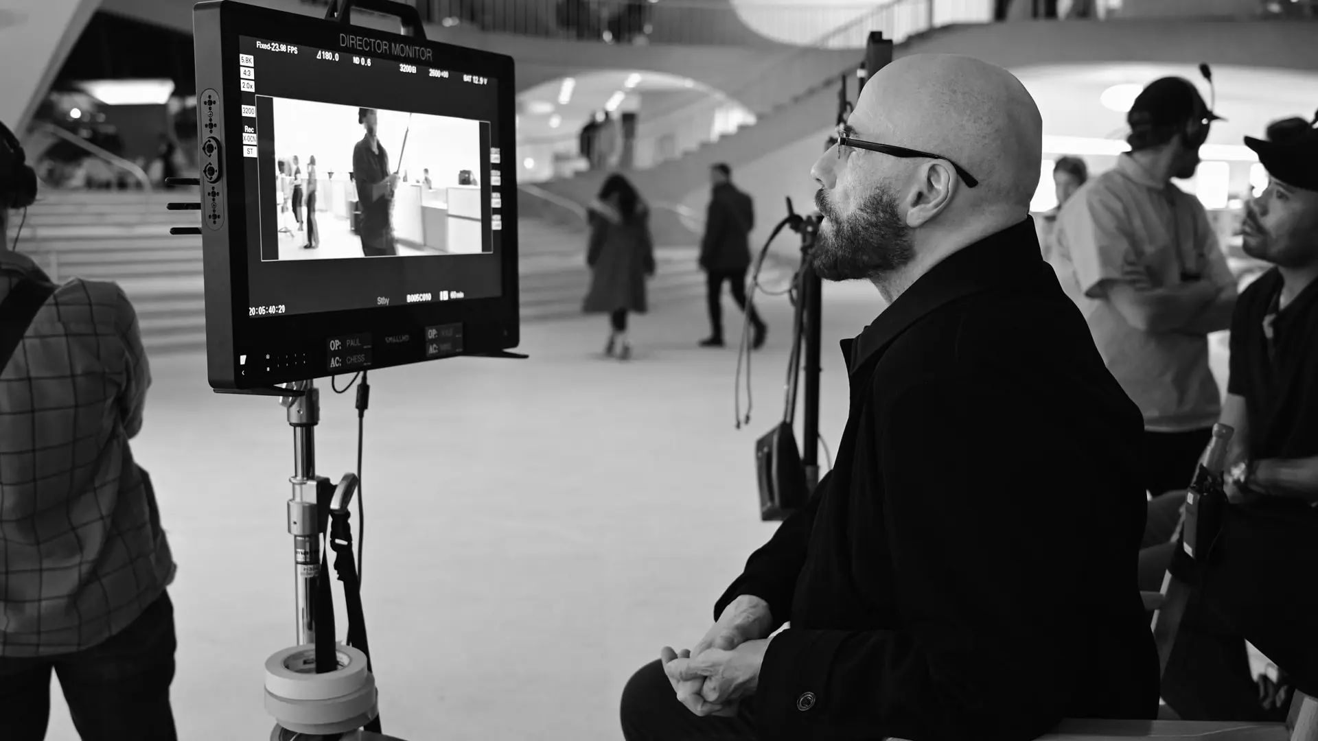 John Travolta nos bastidores de "Propeller One-Way Night Coach". Foto em preto e branco de um homem em frente a um painel
